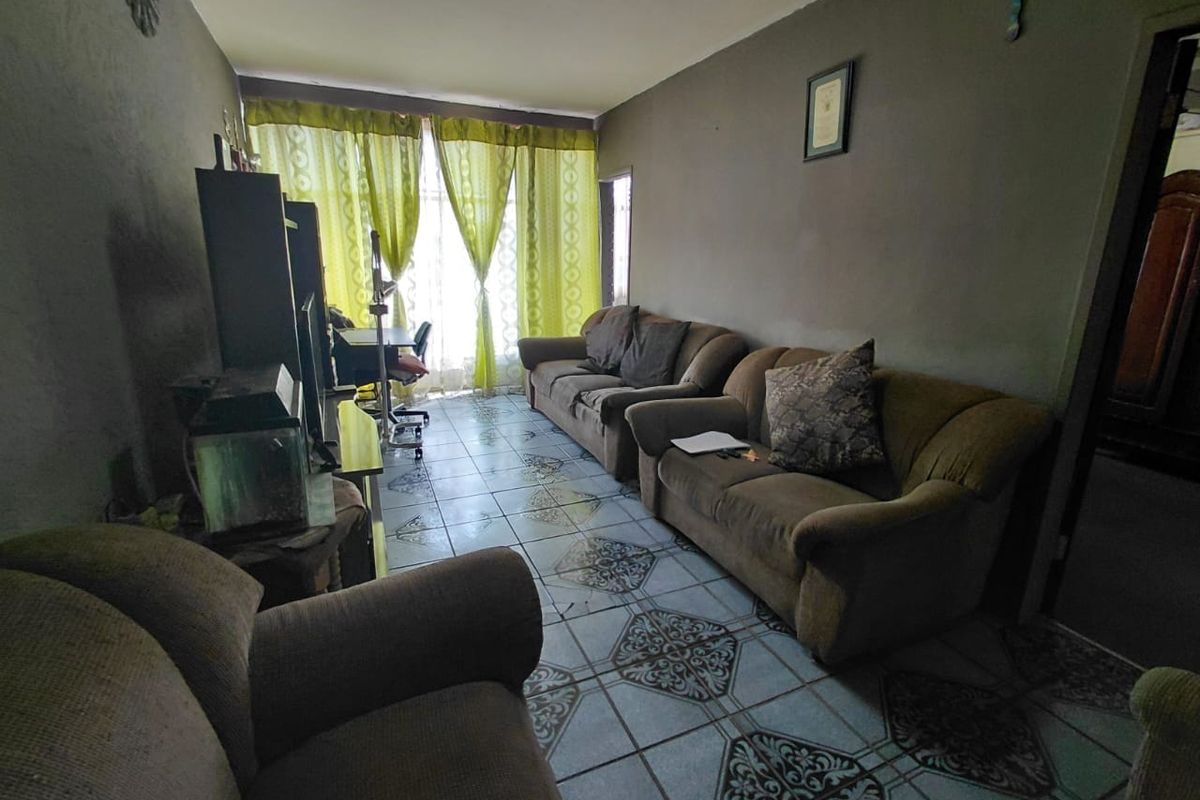 A living room featuring patterned ceramic floor tiles and natural light from a window with curtains.