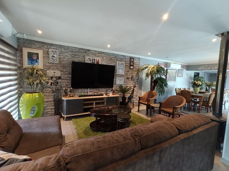 Spacious open-plan living and dining area featuring an exposed brick feature wall, tiled flooring, and a built-in wood burning fireplace.