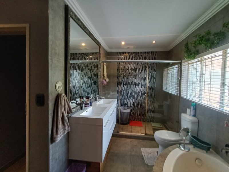 Modern bathroom featuring a double vanity, walk-in shower with mosaic tile accents, a separate bathtub, and large wall-mounted mirror.