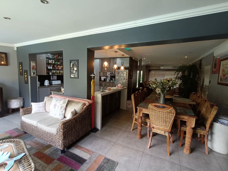 Open-plan living and dining area featuring a central kitchen island, tiled flooring, and a connected scullery space with modern cabinetry.