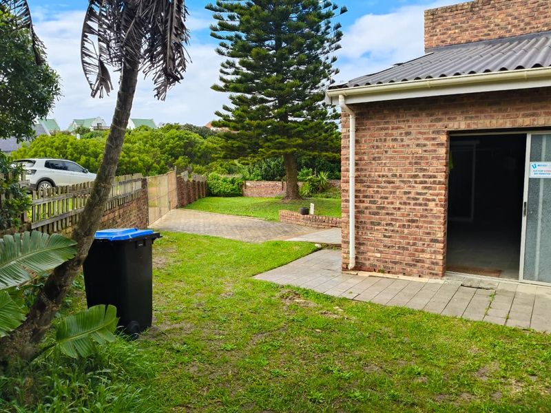 Rear view of the property featuring a face brick exterior, paved patio area, and a private garden with a paved driveway.