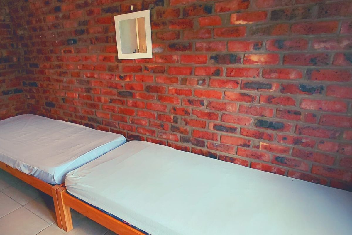 A bedroom featuring an exposed brick feature wall and tiled flooring.