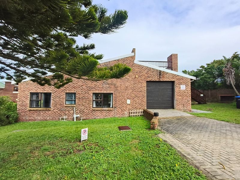Rear view of a face brick house featuring a garage, paved driveway, and an upper-level balcony with an external staircase.