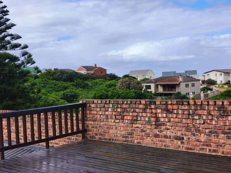 An elevated outdoor balcony featuring timber decking and a brick parapet wall, offering views of the surrounding neighbourhood.