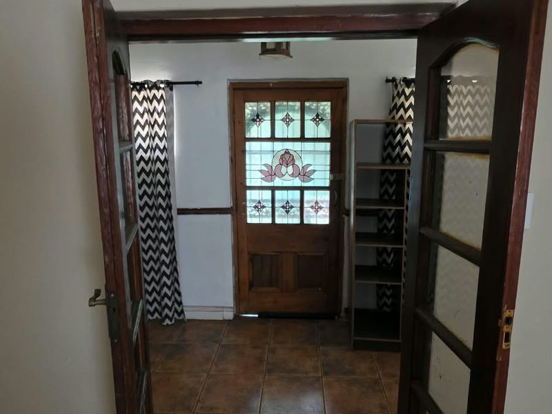 An entry area featuring a decorative stained glass timber door, ceramic tiled flooring, and double timber-framed doors leading into the space.
