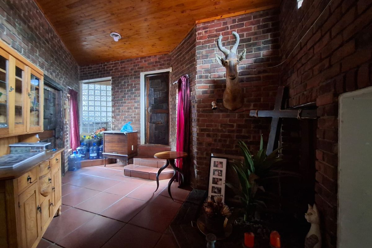 A rustic living area featuring exposed brick walls, a warm timber ceiling, and tiled flooring, offering a unique character-filled space.