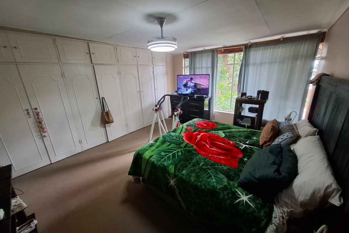 Spacious bedroom featuring extensive built-in cupboards, a ceiling fan, and large windows allowing for natural light.