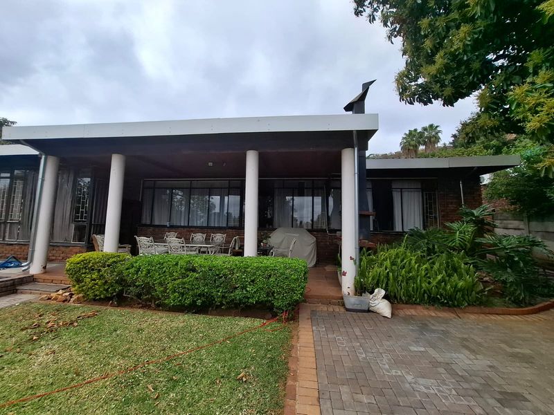 A covered patio area featuring concrete columns, brick paving, and an outdoor fireplace, providing a functional space for outdoor living and entertaining.