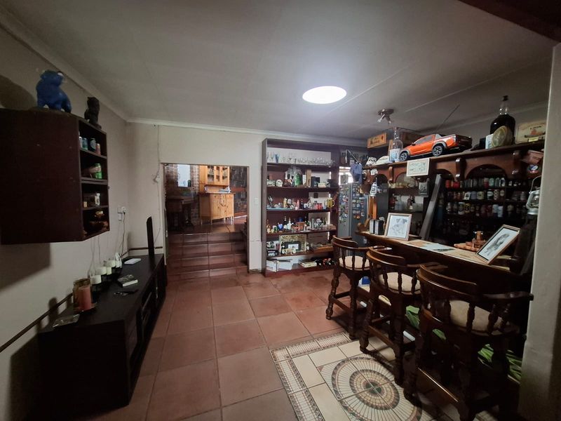 A dedicated home bar area featuring built-in wooden cabinetry, shelving, and tiled flooring, with an open transition to an adjacent room.