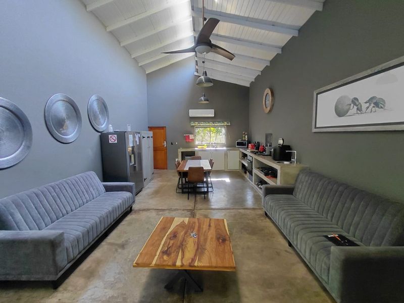 Spacious open-plan living and kitchen area featuring vaulted ceilings with exposed beams, polished concrete floors, and a modern built-in kitchen workspace.