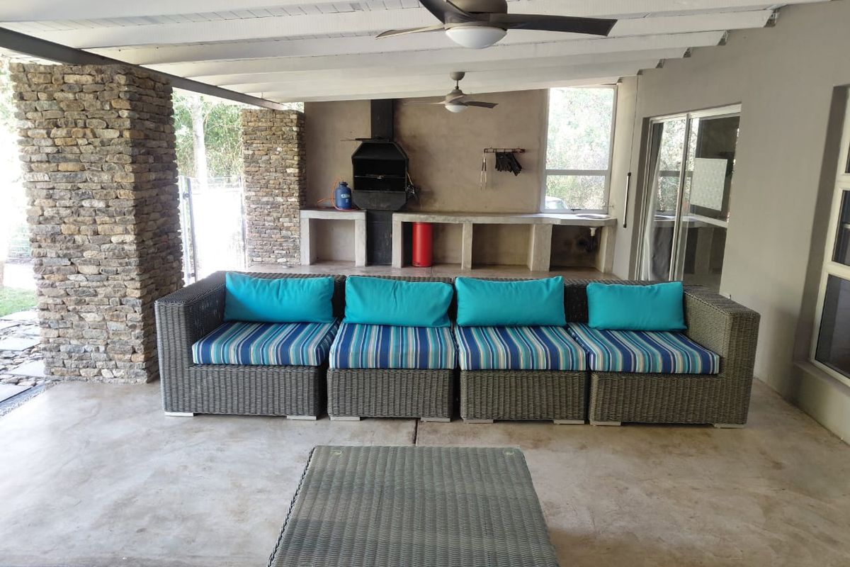 Covered outdoor patio featuring a built-in braai, stone-clad pillars, and concrete prep surfaces, ideal for alfresco dining and entertaining.