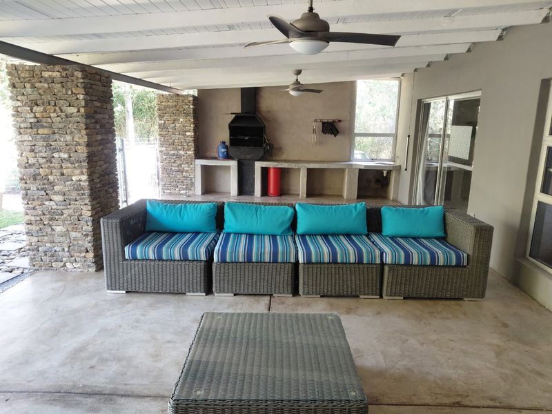 Covered outdoor patio featuring a built-in braai, stone-clad pillars, and concrete prep surfaces, ideal for alfresco dining and entertaining.