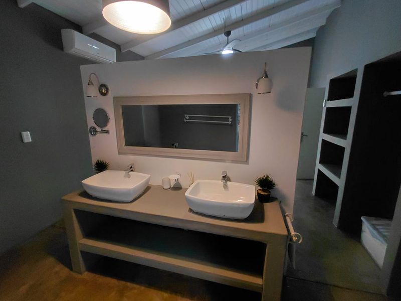 Modern bathroom featuring a double vanity with vessel sinks, built-in shelving, and an exposed beam ceiling with air conditioning.