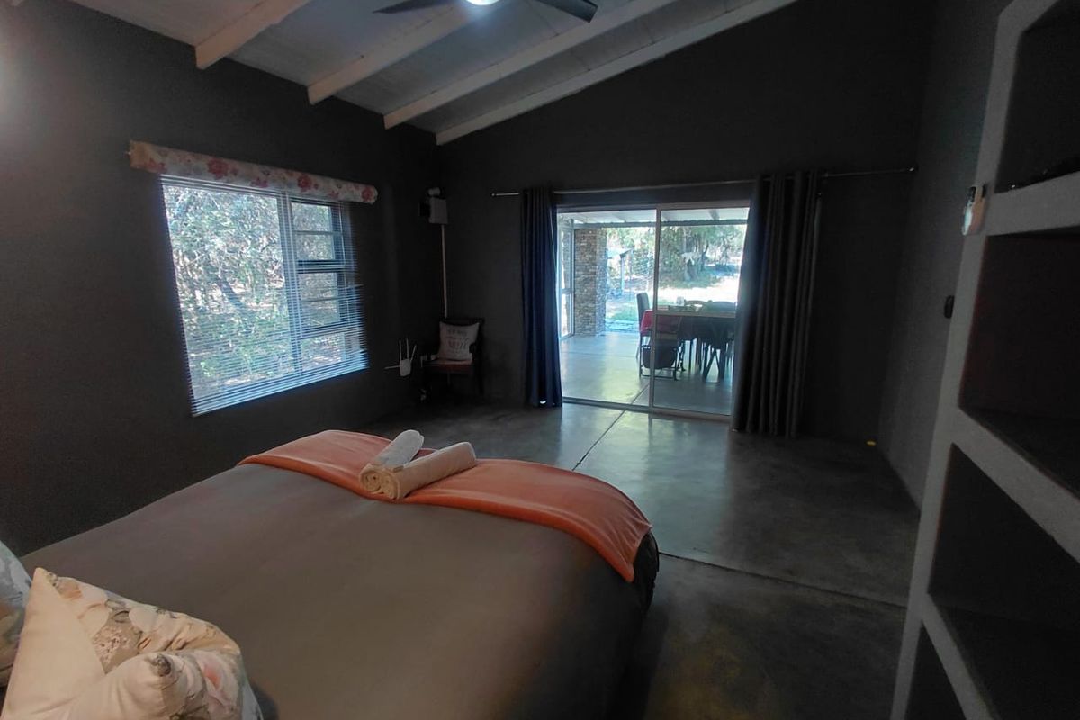 A bedroom featuring exposed beam ceilings, concrete flooring, and a sliding glass door providing access to an outdoor patio area.