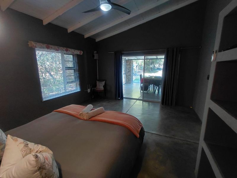 A bedroom featuring exposed beam ceilings, concrete flooring, and a sliding glass door providing access to an outdoor patio area.