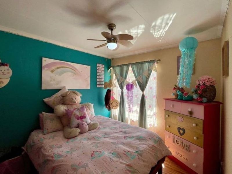 A bedroom featuring a ceiling fan and a window with curtains.
