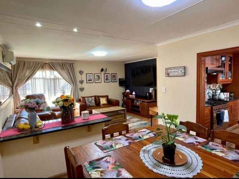 Open plan living and dining area featuring a breakfast bar, recessed lighting, and an adjoining kitchen with built-in cabinetry and appliances.