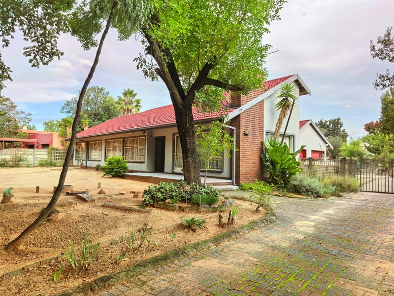 Front view of a single-story house featuring a red tiled roof, brick accents, and a paved driveway leading to the entrance.