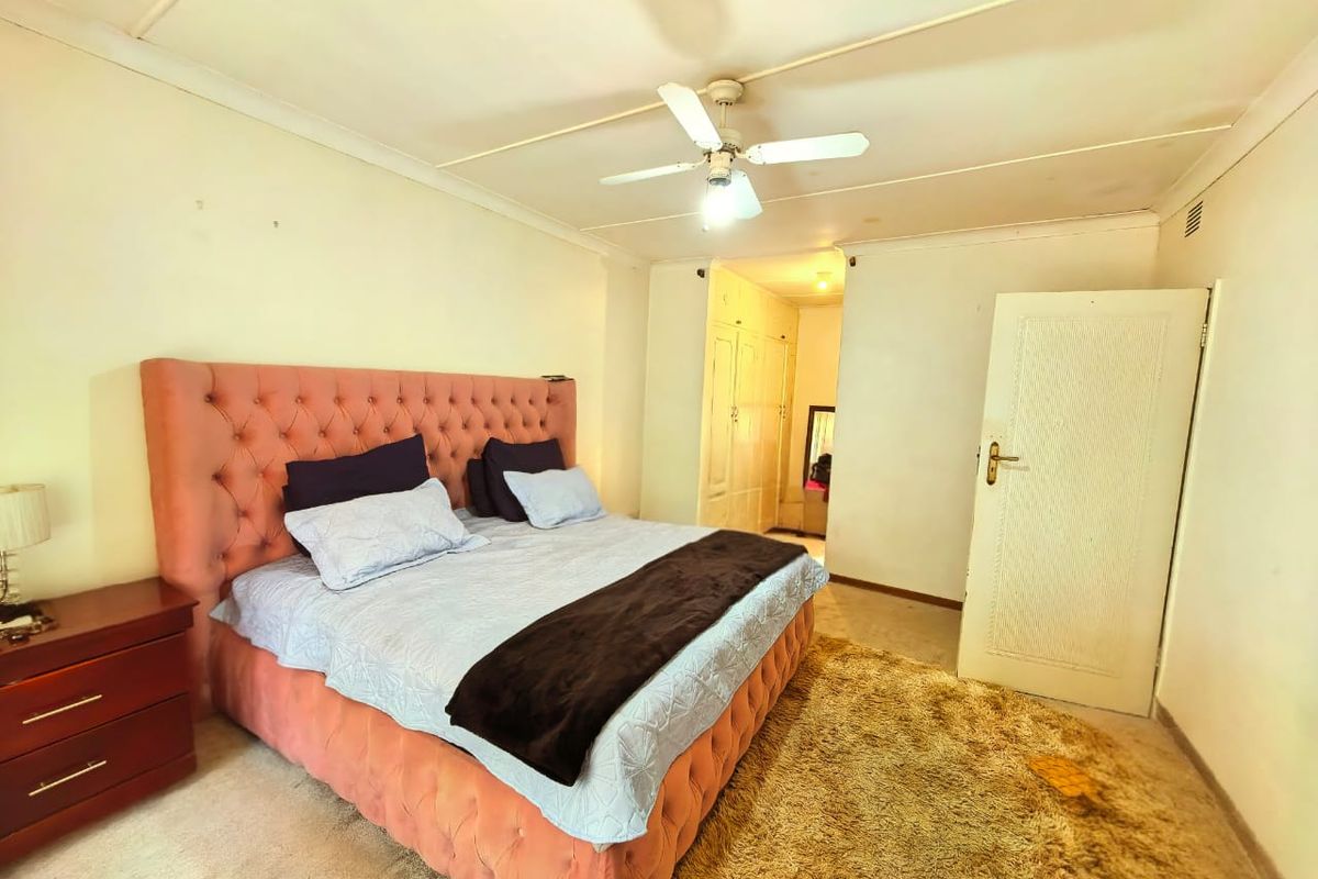 A bedroom featuring built-in cupboards, a ceiling fan, and carpet flooring, requiring some cosmetic updates to the ceiling and finishes.