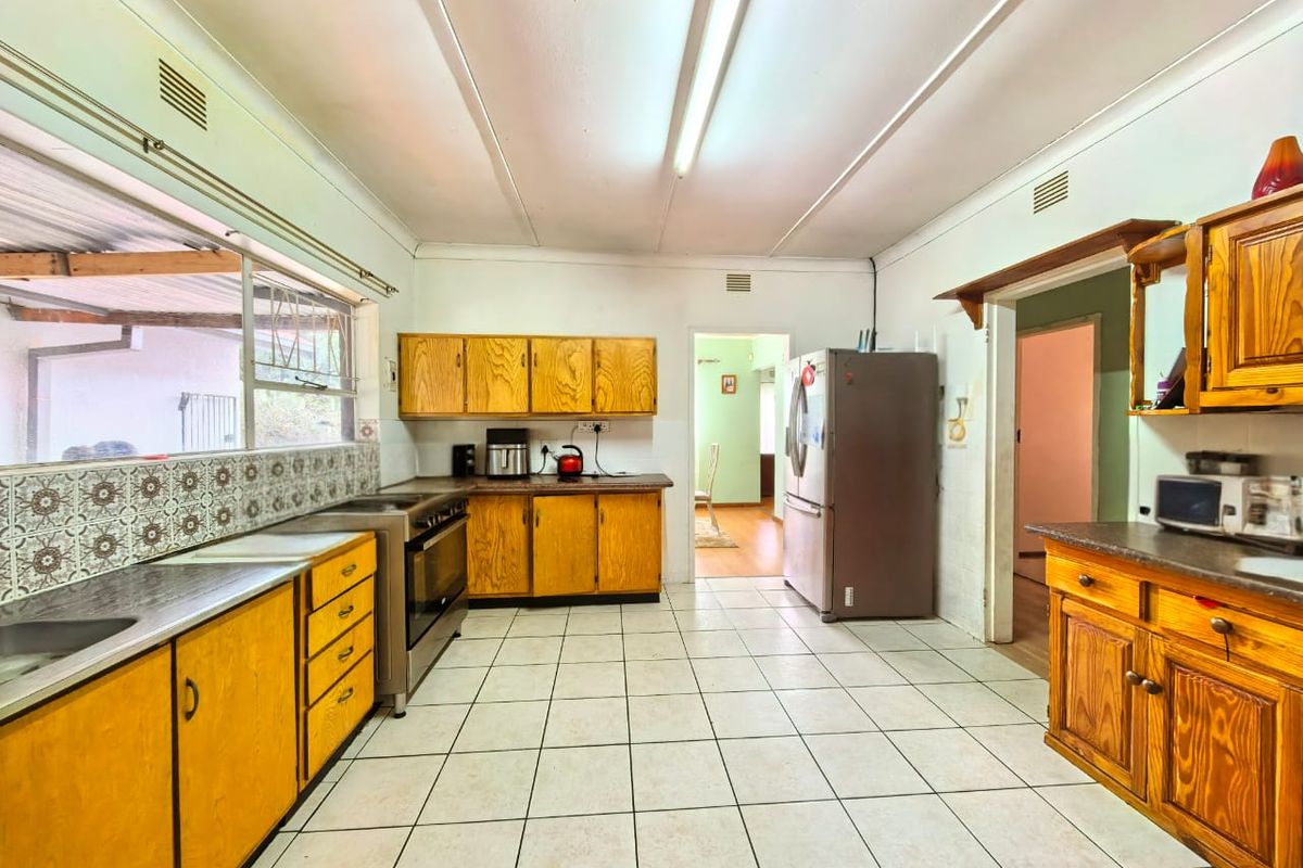 A functional kitchen featuring wooden cabinetry, tiled flooring, and a patterned backsplash, offering a dated aesthetic with potential for modern renovation.