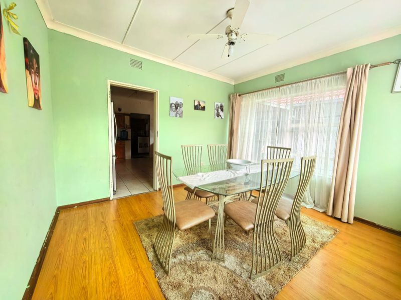 Dining room featuring laminate flooring, ceiling fan, and large window with natural light, providing a functional space for family meals.