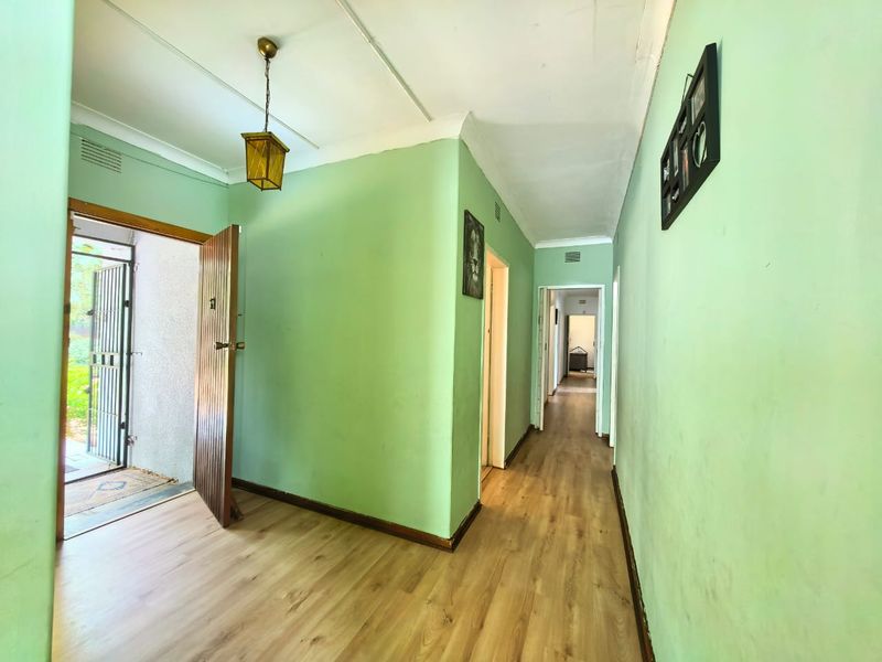 A bright, spacious hallway featuring laminate flooring and a neutral layout, providing access to multiple rooms throughout the home.