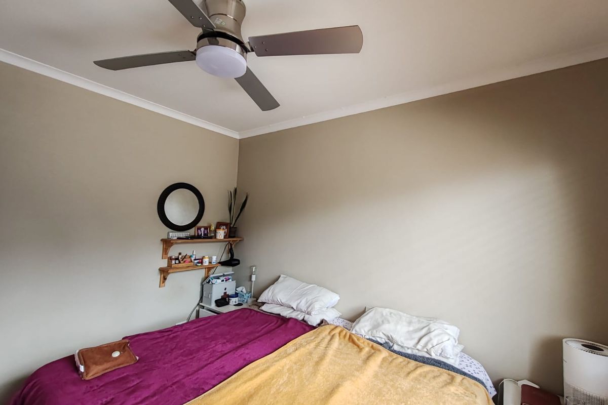 A bedroom featuring a ceiling fan and neutral wall tones, providing a functional space with built-in wall shelving.