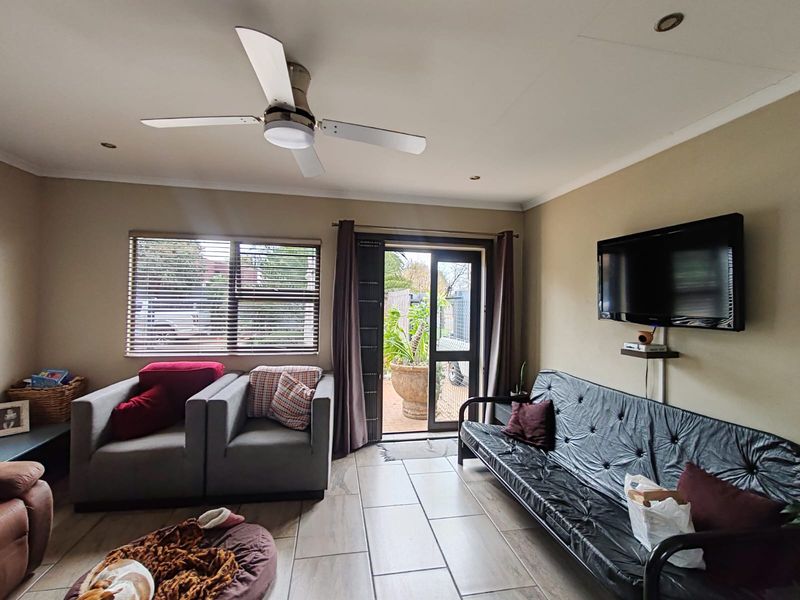 A comfortable living room featuring tiled flooring, a ceiling fan, recessed lighting, and direct access to an outdoor patio area through a sliding glass door.