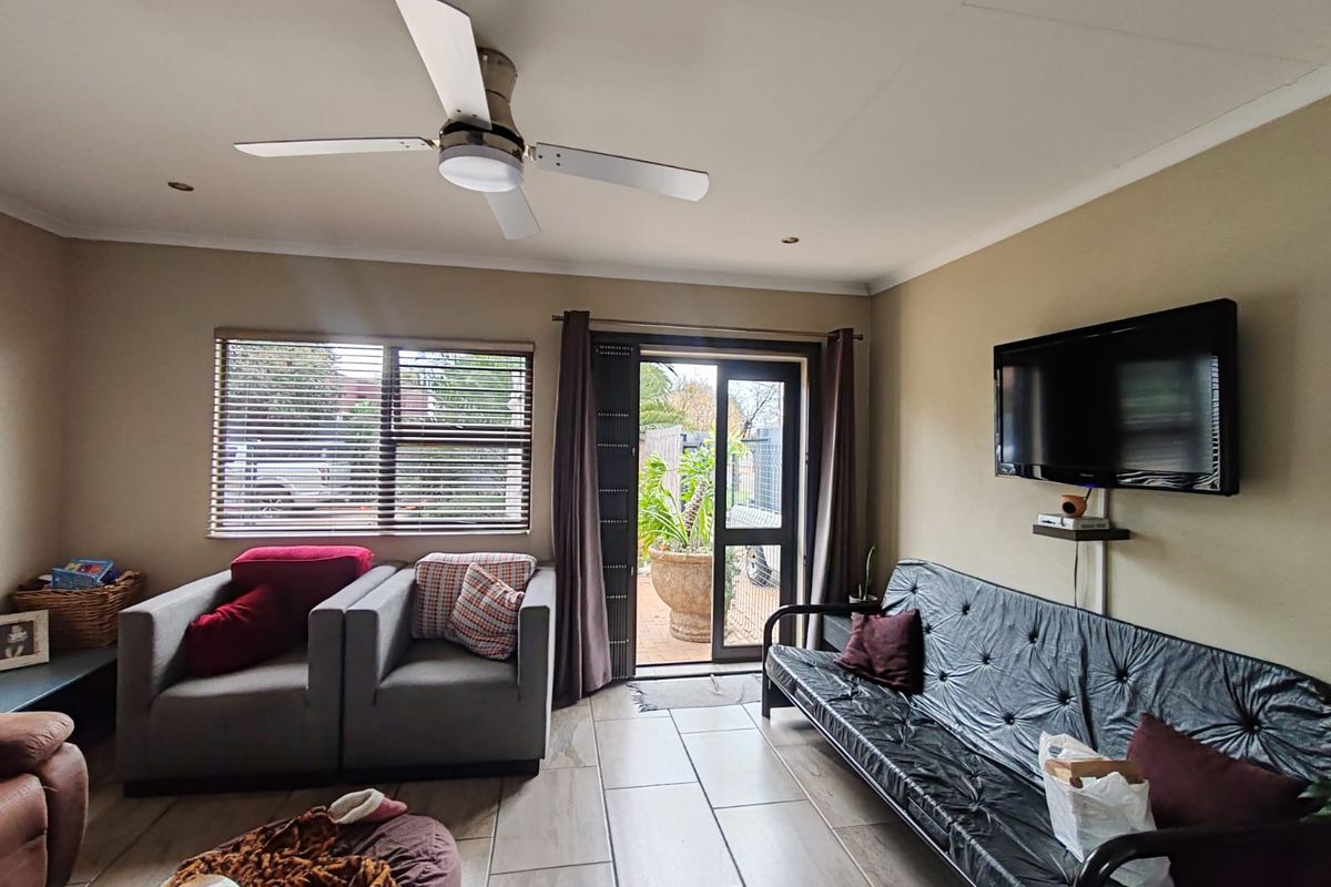 A comfortable living room featuring tiled flooring, a ceiling fan, recessed lighting, and direct access to an outdoor patio area through a sliding glass door.
