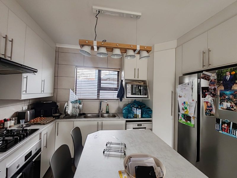 A modern, well-equipped kitchen featuring white cabinetry, a gas hob, integrated appliances, and a central island with pendant lighting.