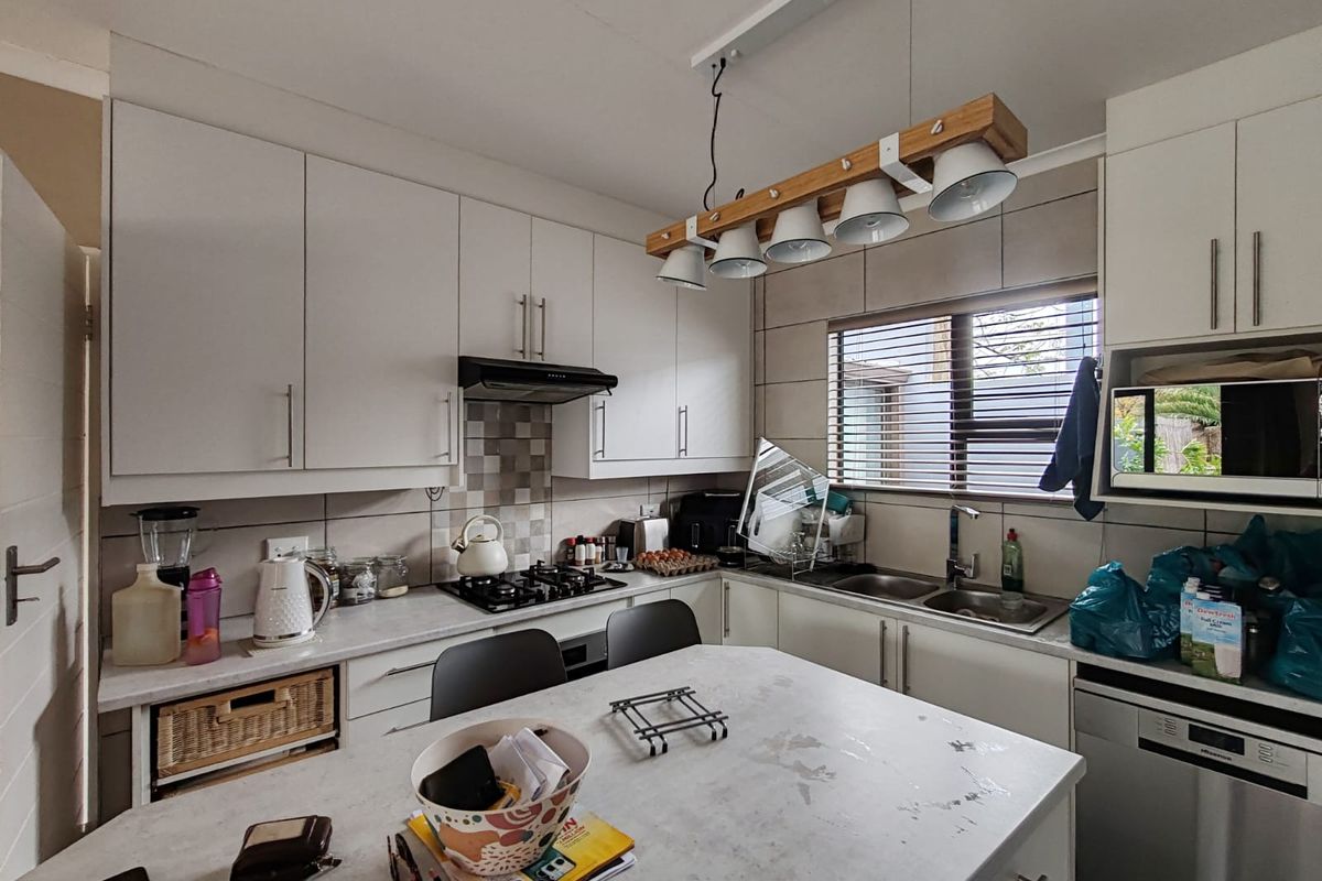 A functional kitchen featuring white cabinetry, a gas hob, extractor fan, double sink, and a central island with a laminate countertop.