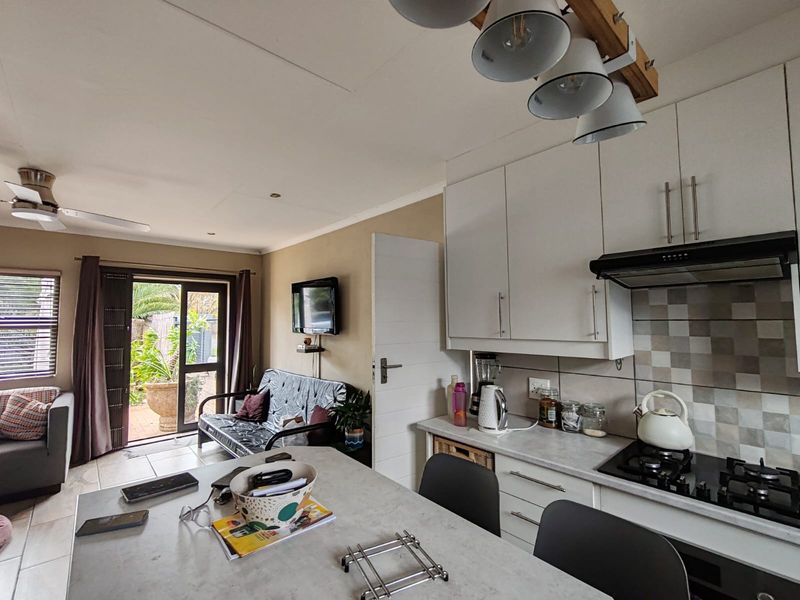 Open-plan living and kitchen area featuring modern cabinetry, gas hob, extractor fan, and direct access to the outdoor patio through sliding glass doors.