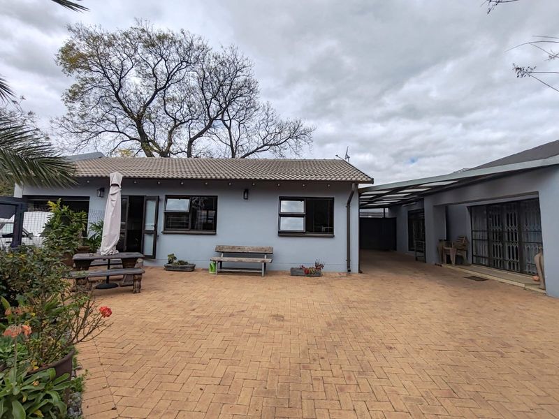A well-maintained rear courtyard featuring paved flooring, a tiled roof cottage structure, and a covered walkway providing access to the main dwelling.