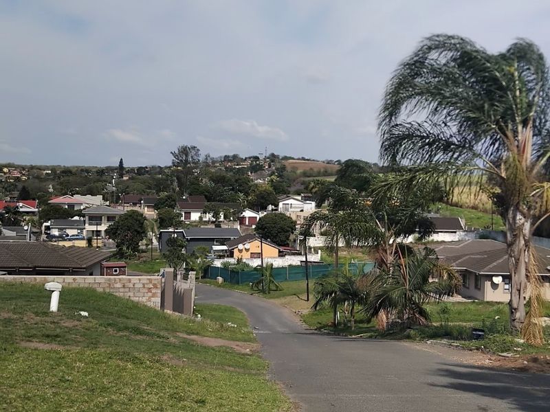 A view looking down a paved residential street in a suburban neighborhood, showing surrounding houses and landscaped verges.
