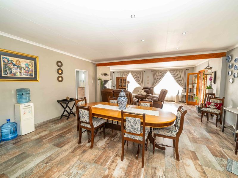 Spacious open-plan living and dining area featuring timber-look tiled flooring, recessed lighting, and an exposed timber beam, creating a warm and inviting atmosphere.