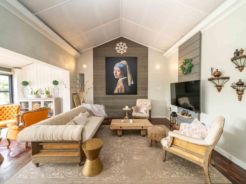 Spacious living room featuring a vaulted ceiling, hardwood flooring, and a prominent timber plank feature wall with integrated television mounting.