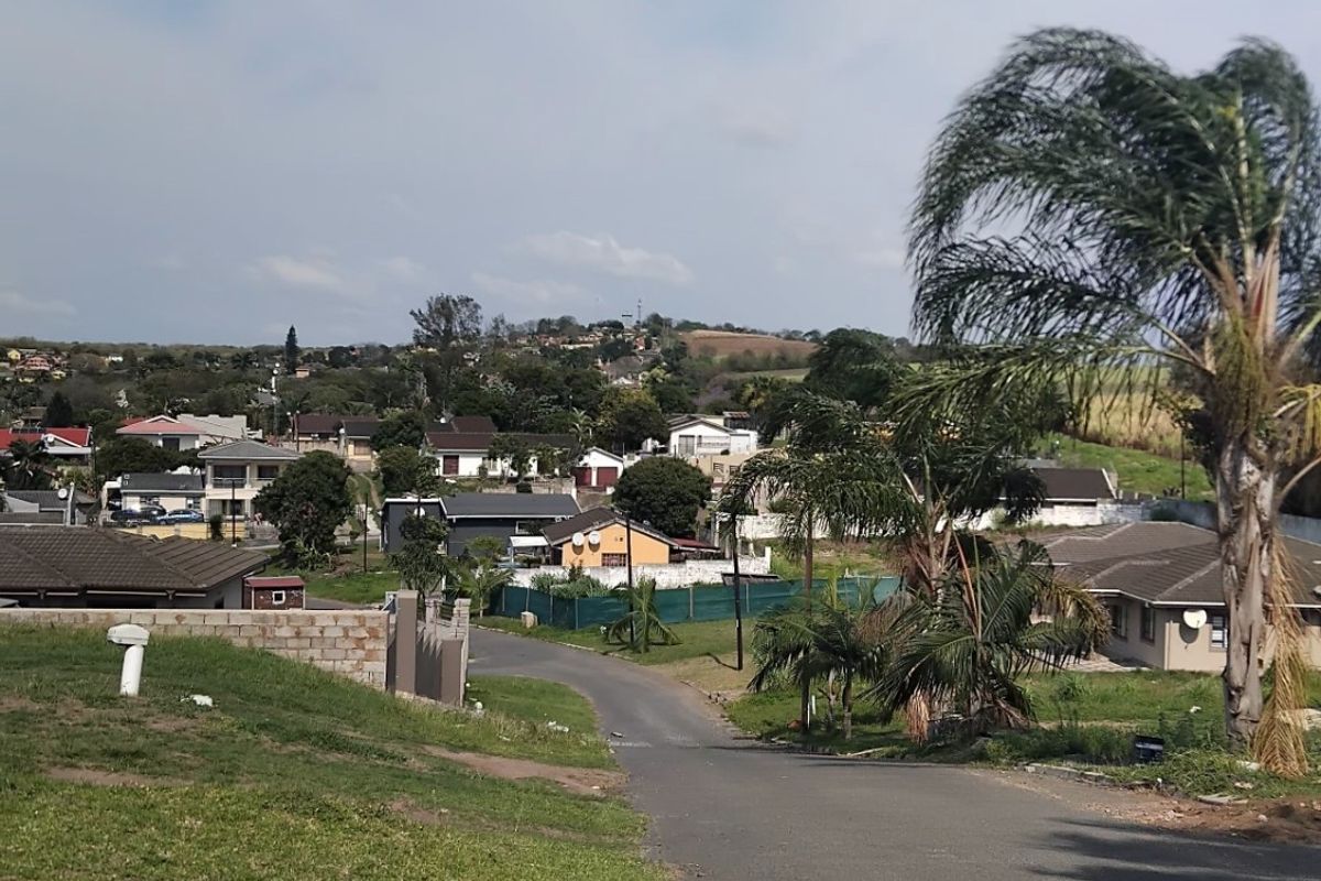 A view looking down a paved residential street in a suburban neighborhood, showing surrounding houses and landscaped verges.