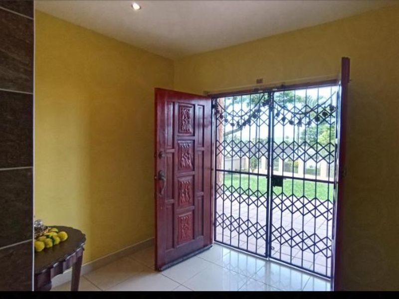 Entrance area featuring a solid wood front door, security gate, tiled flooring, and recessed downlighting.