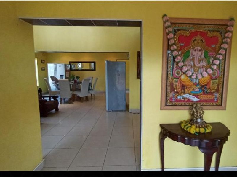 A view from a yellow-walled room looking through a doorway into an adjacent living and dining area with tiled flooring.