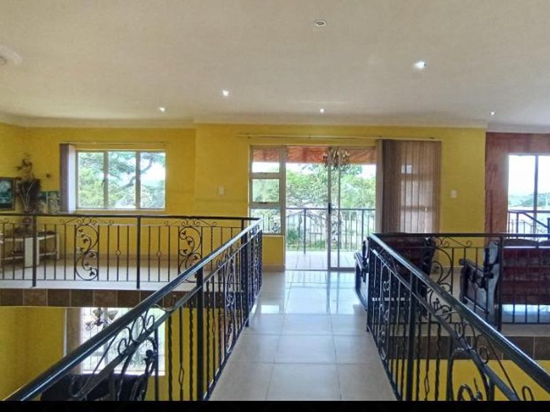 An elevated living area featuring a wrought iron balustrade, tiled flooring, and sliding glass doors leading to an outdoor space.