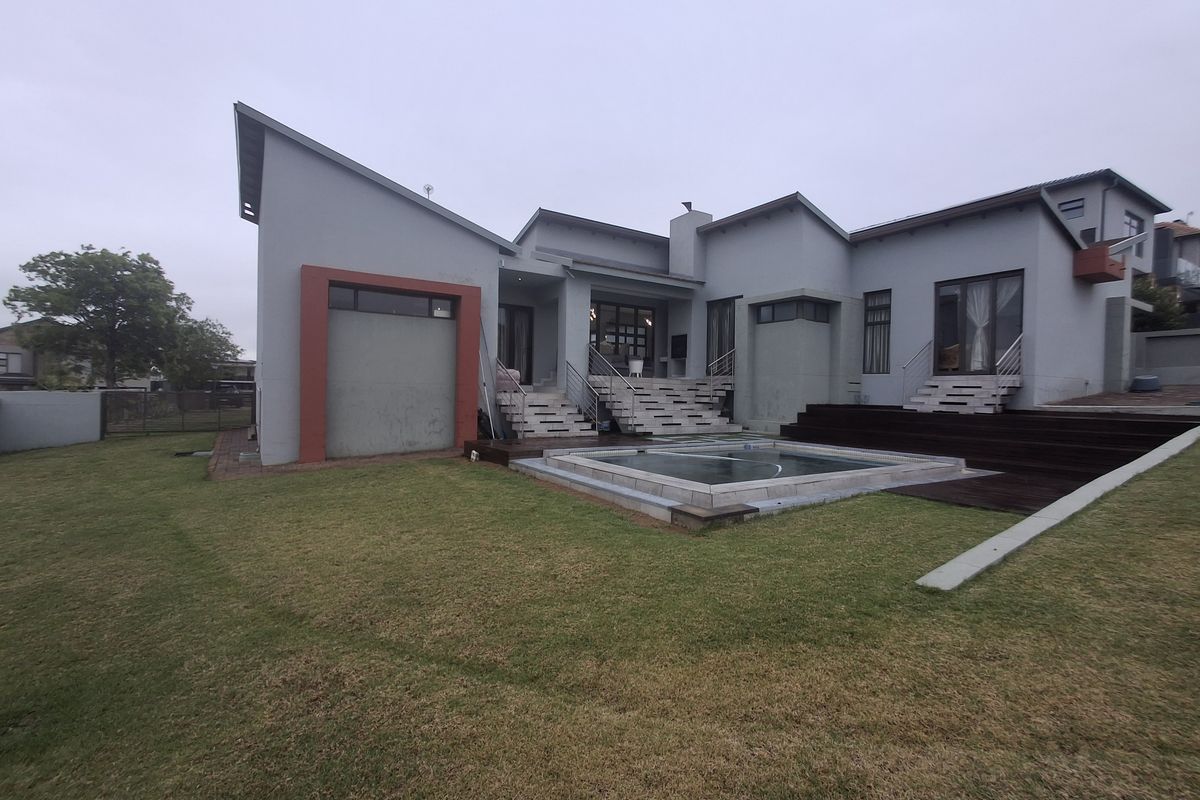 Rear elevation of a modern house featuring a swimming pool, timber decking, and concrete stairs leading to the main living areas.