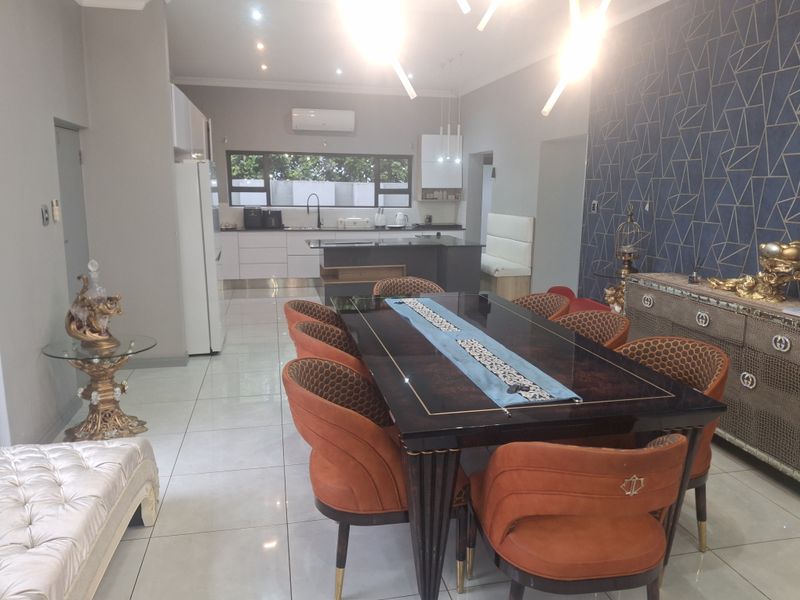 Spacious open-plan living and dining area featuring a modern kitchen with island, tiled floors, and contemporary lighting.