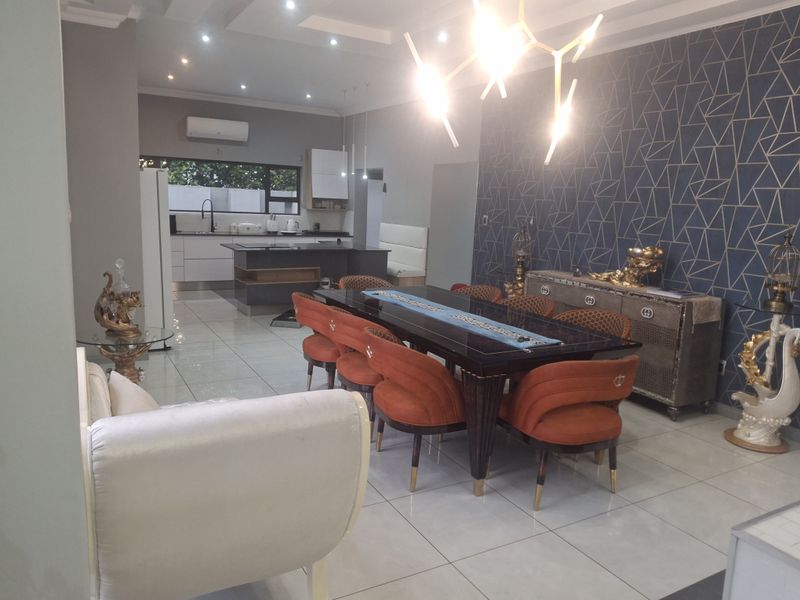 Spacious open-plan living and dining area featuring modern porcelain tiling, recessed ceiling lighting, and a contemporary kitchen with a central island.