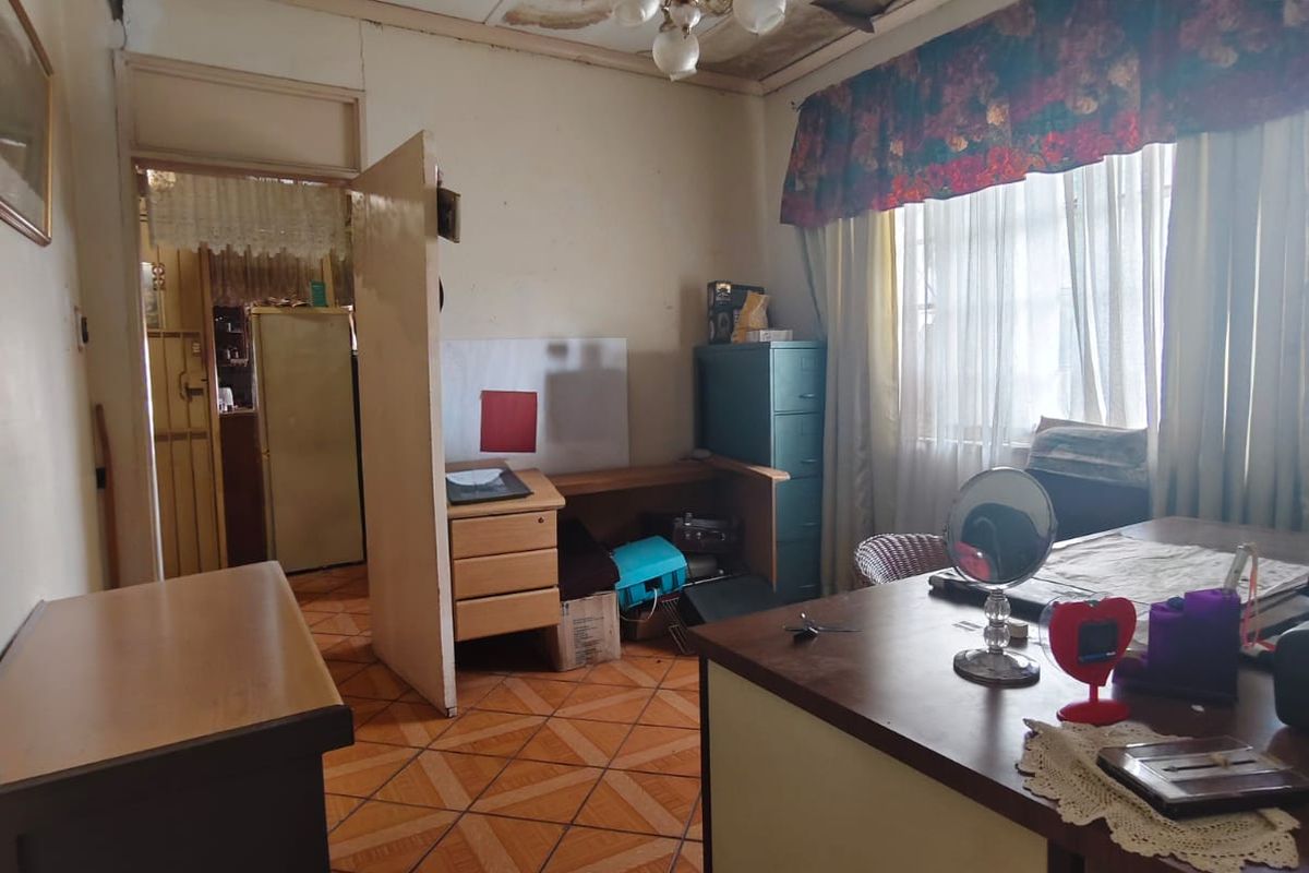 A living room space featuring tiled flooring and a ceiling light fixture, currently showing significant signs of water damage and ceiling deterioration.