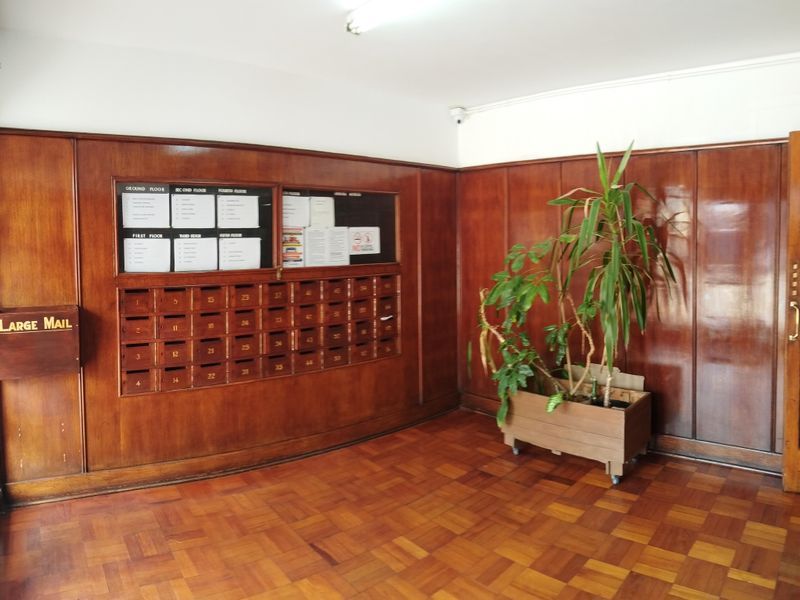 A well-maintained building entrance lobby featuring classic wood paneling, parquet flooring, and a wall-mounted bank of mailboxes.
