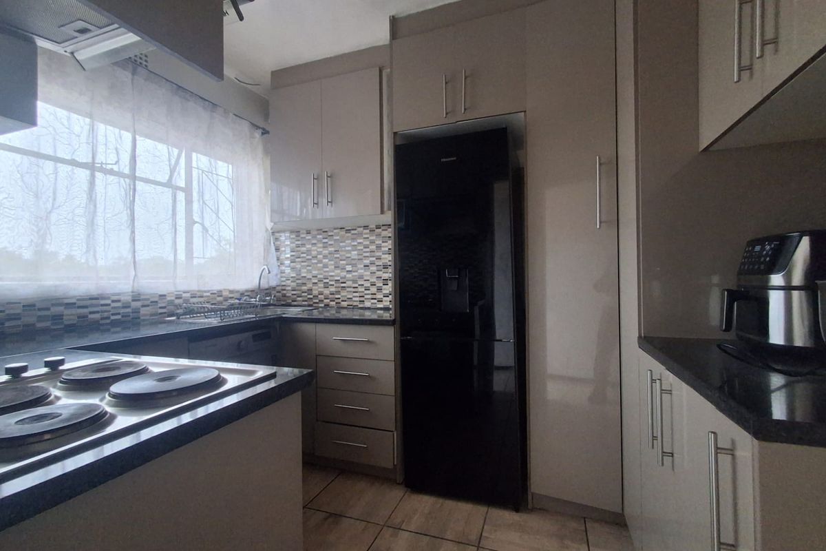 Modern kitchen featuring sleek built-in cabinetry, granite countertops, a mosaic tile backsplash, and integrated electric hob with extractor fan.