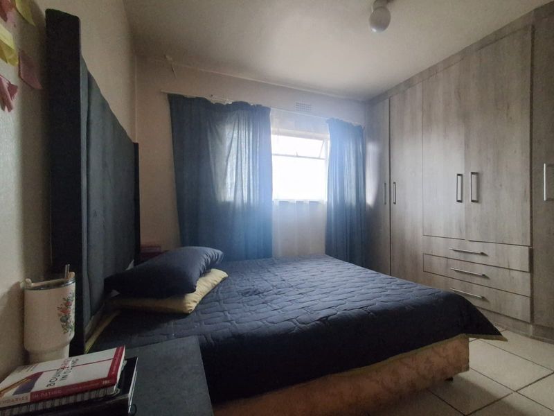 A bedroom featuring built-in cupboards and tiled flooring, providing functional storage space.