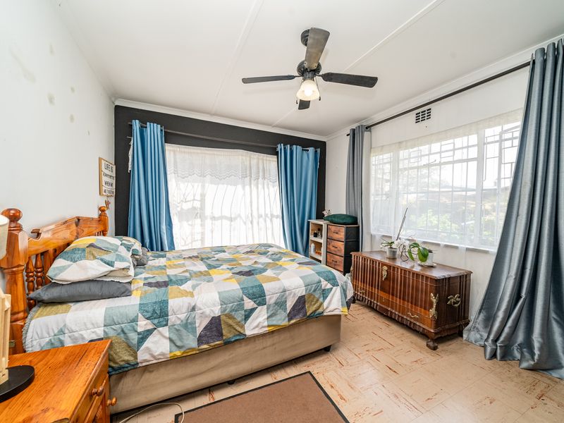 A bedroom featuring vinyl tile flooring, a ceiling fan, and security bars on the windows, with some visible wall staining and wear.