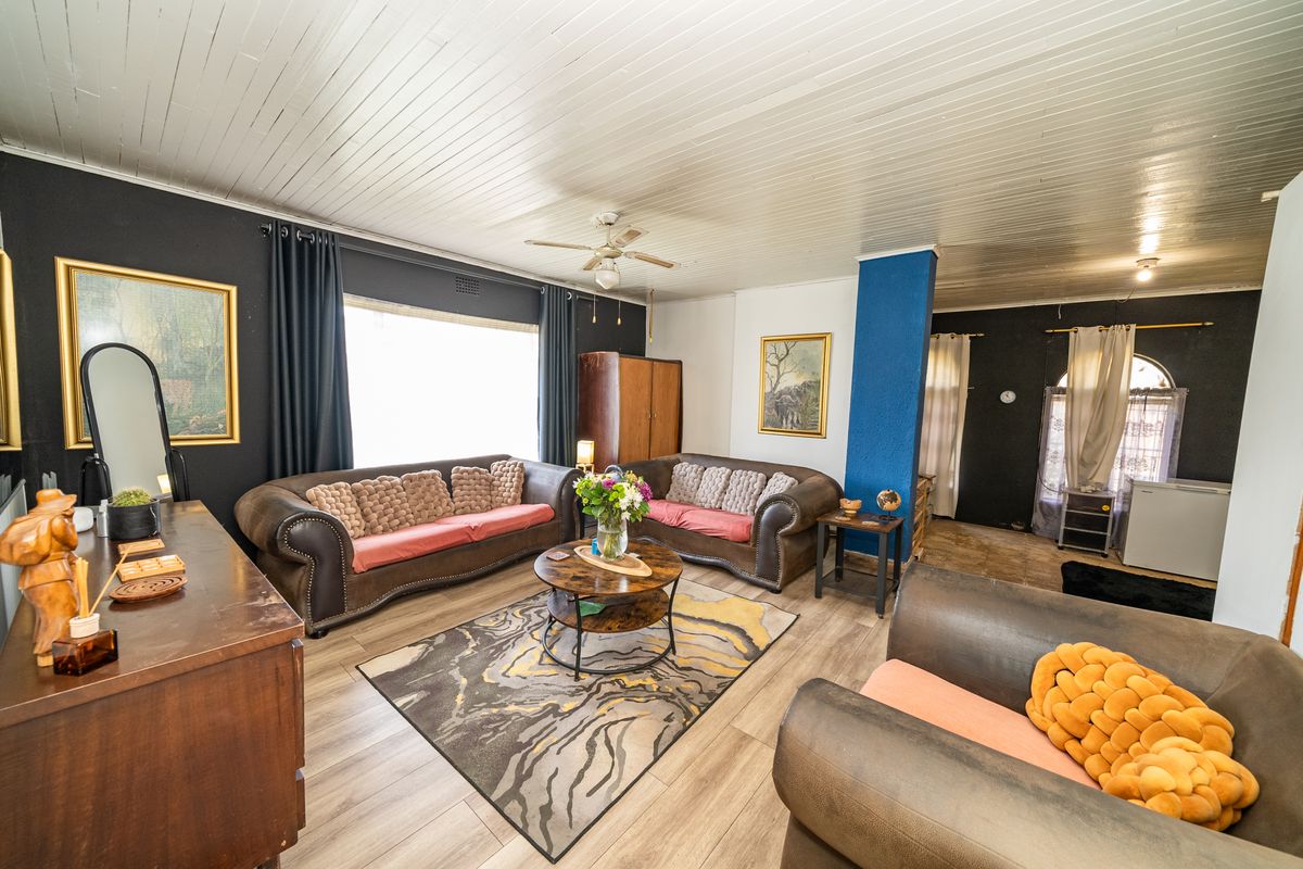 Spacious living room featuring timber-look laminate flooring, a ceiling fan, and a distinctive tongue and groove ceiling design.