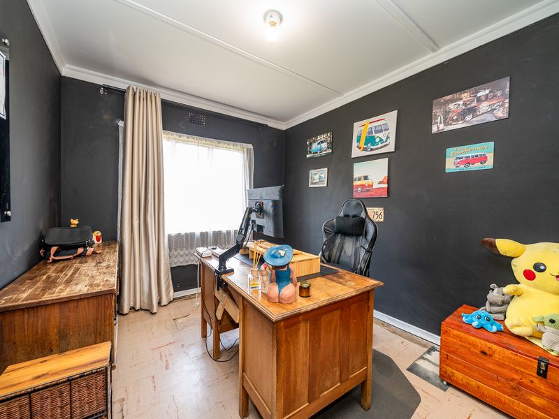 A home office space featuring dark painted walls and worn flooring, offering a functional area for work or study.